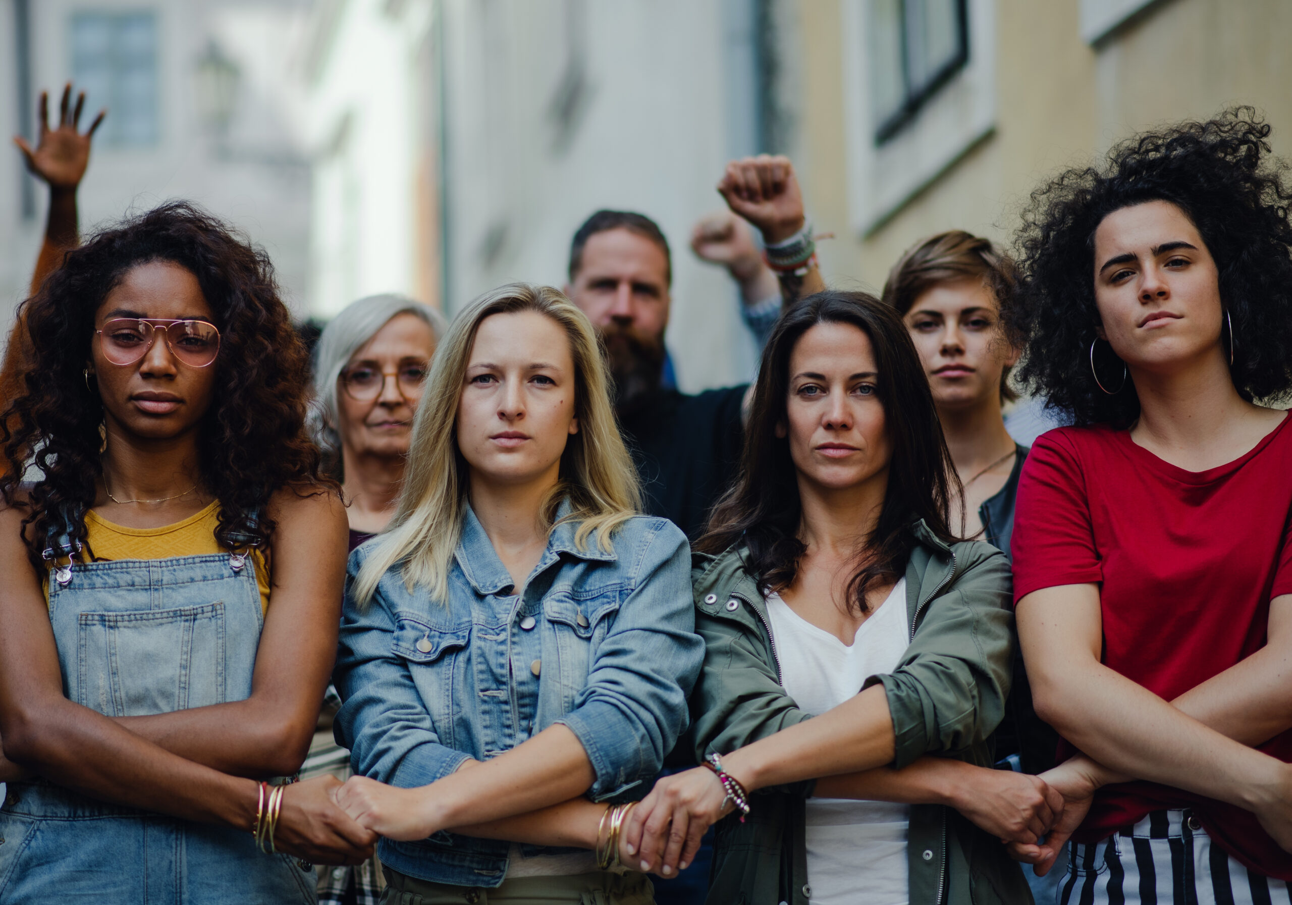 Group of people activists protesting on streets, women march and demonstration; women in front link arms in solidarity