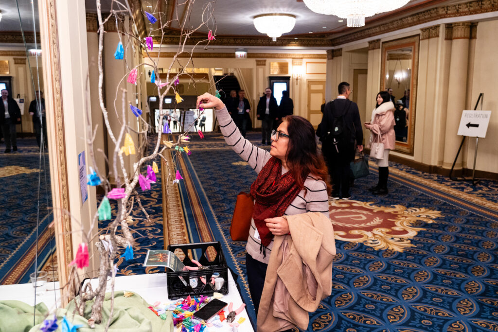 CIES2025AnnualConference Woman adds a paper crane to a tree of cranes at CIES 2025